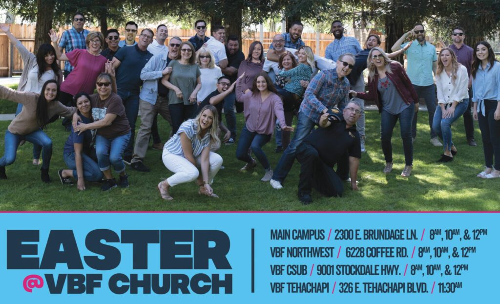 A large group of diverse people smiling and posing together outdoors in a park-like setting.